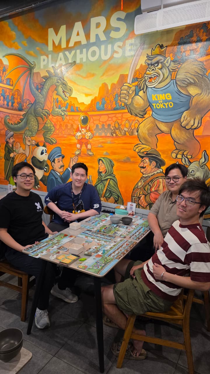 Empat orang duduk bersama mengelilingi boardgame di Mars Playhouse
